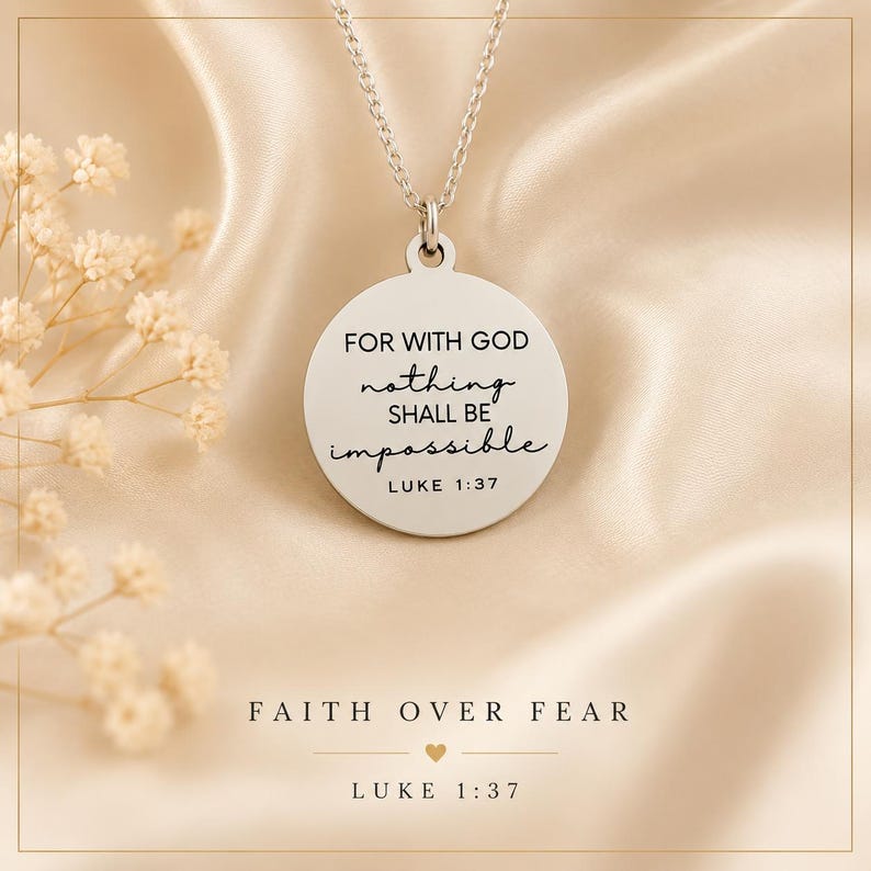 Op de afbeelding: Een zilverkleurige ronde hanger aan een ketting met de gegraveerde tekst 'FOR WITH GOD nothing SHALL BE impossible LUKE 1:37'. De hanger hangt aan een fijne zilveren ketting, geplaatst boven de tekst 'FAITH OVER FEAR' en 'LUKE 1:37'.