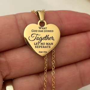May include: A gold-colored heart-shaped pendant necklace. The pendant has the inscription "WHAT GOD HAS JOINED TOGETHER, LET NO MAN SEPERATE Matt 19:6". The necklace has a delicate chain.