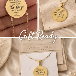 Op de afbeelding: Een goudkleurige ketting met een ronde hanger voorzien van de gegraveerde tekst: When my heart is overwhelmed; lead me to The Rock that is higher than I, Psalm 61:2. De ketting wordt gepresenteerd op een witte displaykaart met de tekst Wrapped in Love Charms.