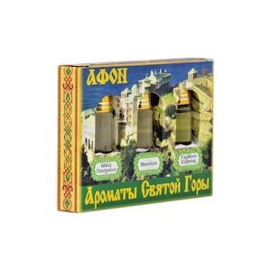 Peut inclure: Un coffret contenant trois petits flacons de parfum. La boîte présente une image panoramique d'un monastère et du texte en grec. Les flacons ont des bouchons dorés et sont étiquetés en grec. La boîte a une bordure verte et dorée.