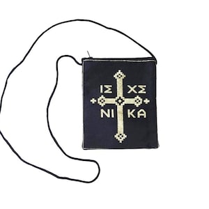 May include: A dark blue religious pendant with a gold cross and Greek text. The pendant is square-shaped and has a black cord for wearing. The text reads "ΙΣ ΧΣ ΝΙΚΑ".