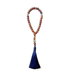Peut inclure: Un collier de prière en bois avec un pompon bleu et un pendentif en forme de croix dorée.