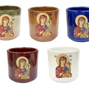 Puede incluir: Conjunto de cinco tazas de cerámica con un diseño de icono religioso. Las tazas son de varios colores, incluyendo verde, marrón, azul, rojo y blanco. Cada taza presenta una representación de María y Jesús, con el texto "MP OY" en la taza.
