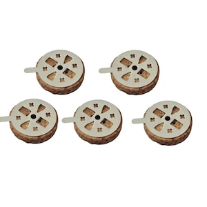 Könnte beinhalten: Fünf Flaschenverschlüsse mit einem Naturkork-Sockel und einer silberfarbenen Metalloberseite. Die Metalloberseite hat ein kreisförmiges Design mit einem Griff und dekorativen Aussparungen. Die Verschlüsse sind auf weißem Hintergrund angeordnet.