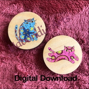 Puede incluir: Dos posavasos de madera con diseño de gato. El primer posavasos presenta un gato azul con un patrón floral. El segundo posavasos presenta un gato rosa con un patrón geométrico.