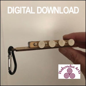 May include: A wooden keychain with a small wooden box and six white pegs. The keychain has a black carabiner clip and the text "Habondia Arts" is printed on the wooden box.