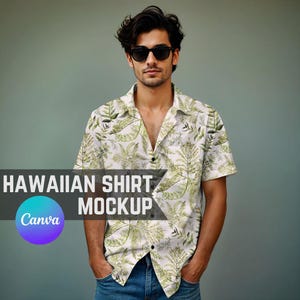 以下が含まれることがあります： 緑と白のトロピカルな葉のプリントが施された白いボタンダウンシャツ。シャツは半袖で襟付き。モデルはシャツを青いジーンズとサングラスと合わせて着用しています。