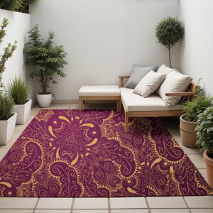 May include: A purple and gold patterned area rug with a floral design. The rug is laid out on a tiled patio with a wooden bench and potted plants.