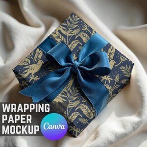 Op de afbeelding: Een vierkante geschenkdoos verpakt in marineblauw papier met een gouden botanisch patroon en een grote blauwe satijnen strik. De tekst "WRAPPING PAPER MOCKUP" is zichtbaar.