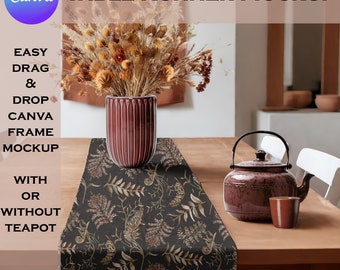 May include: A black table runner with a floral pattern featuring brown and beige leaves. The runner is on a wooden table with a brown teapot and a brown cup. The table runner is styled with a vase of dried flowers.