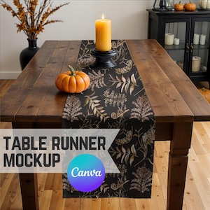 May include: A black and gold table runner with a floral pattern. The runner is on a wooden table with a pumpkin and a candle on it. The text "Table Runner Mockup Canva" is on the image.