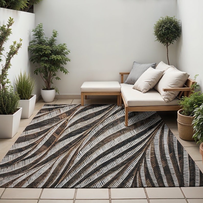 May include: A brown and white patterned outdoor rug with a geometric design. The rug is placed in a patio setting with a white couch and a wooden coffee table.