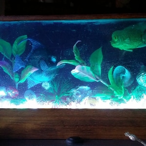 Aquarium. Kunstobjekt aus Epoxidharz, das ein Aquarium darstellt, das auf einem Holzsockel ruht. LED-Lampe