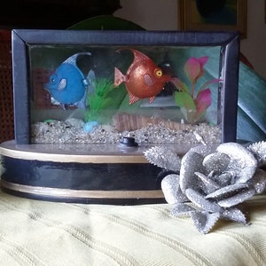 Aquarium. Kunstobjekt aus Epoxidharz, das ein Aquarium darstellt, das auf einem Holzsockel ruht. LED-Lampe