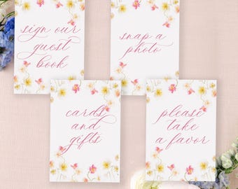 May include: Four white cards with pink floral borders and pink calligraphy text. The cards read "Sign our guest book", "Snap a photo", "Cards and gifts", and "Please take a favor".