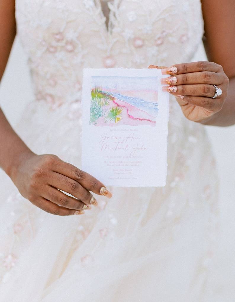 May include: A white wedding invitation with a watercolor illustration of a beach scene. The invitation reads "James and Michael John" with the date and location of the wedding.