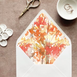 May include: A white envelope with a watercolor design of orange, yellow, and brown leaves on the flap.