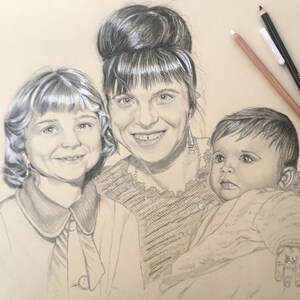 May include: A black and white pencil drawing of three people. A woman with dark hair is holding a baby in her arms. A young girl with light hair is standing next to the woman. The drawing is on a light brown background.