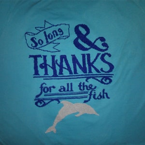 May include: A light blue t-shirt with a blue embroidered design that says "So long & THANKS for all the fish" with a white dolphin silhouette below the text.