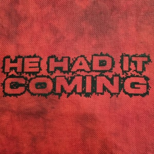 Puede incluir: Bordado de punto de cruz en tela roja con la frase "He had it coming" en hilo negro.