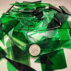 May include: A pile of green glass shards, some with a textured surface, with a silver coin on top.