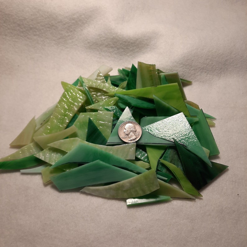 May include: A large pile of green and white glass mosaic tiles in various shapes and sizes. The tiles are arranged in a random pattern and are perfect for crafting projects.