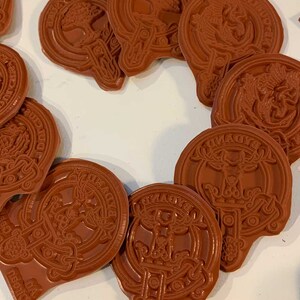 Pode incluir: Uma cole&ccedil;&atilde;o de 12 carimbos de borracha marrom com v&aacute;rios desenhos, incluindo uma &aacute;rvore, um veado e um p&aacute;ssaro. Os carimbos est&atilde;o dispostos em c&iacute;rculo sobre uma superf&iacute;cie branca.