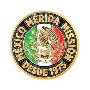 May include: A gold-colored round coin with a black border and the text "MEXICO MERIDA MISSION DESDE 1975". The center of the coin features the Mexican coat of arms with a golden eagle on a cactus, a snake in its beak, and a green and red background.