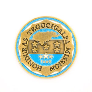 May include: A gold-colored metal coin with a blue border. The coin features the text "Honduras Tegucigalpa Mission 1980" and a map of Honduras with five stars.