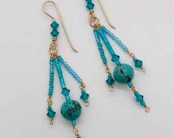 May include: A pair of turquoise and gold dangle earrings with a turquoise stone and crystal accents.