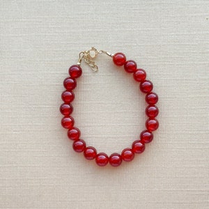Peut inclure: Un bracelet en perles de cornaline rouge avec un fermoir en or.
