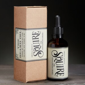 May include: A brown cardboard box with a white label that reads "The Beard Oil 50 ml / 1.69 fl oz Made in the UK" and a brown glass bottle with a dropper and a white label that reads "The Gentleman's Choice Squire Original Product".