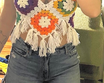 Puede incluir: Top halter de ganchillo con diseño floral multicolor. El top tiene borlas blancas y se combina con shorts vaqueros. Los colores incluyen morado, naranja, verde y blanco. Una prenda hecha a mano de estilo bohemio.