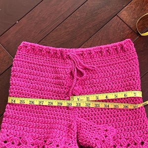 Pink adult crochet shorts, Pink crochet shorts with a drawstring waist. Scalloped hem. The shorts are made of a soft, lightweight yarn