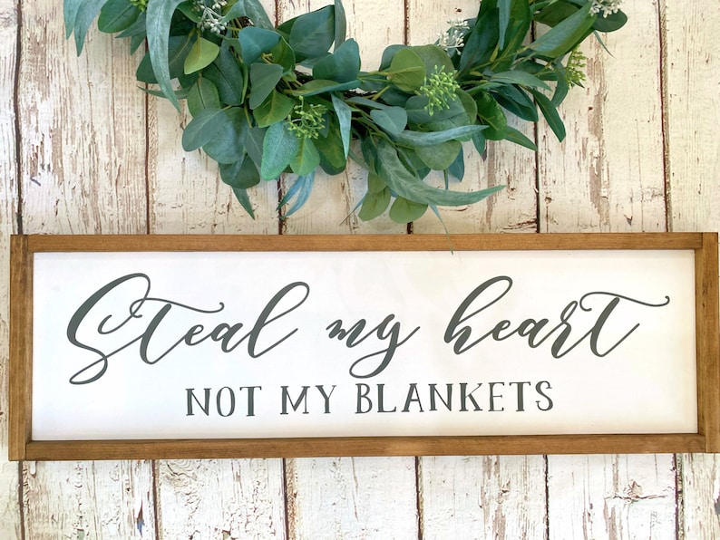May include: A wooden sign with a white background and a brown frame. The sign says "Steal my heart not my blankets" in black cursive lettering.