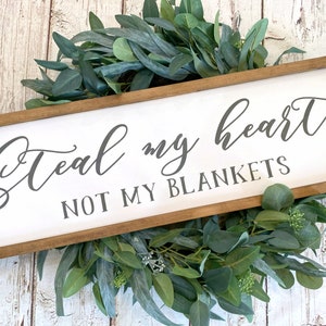 May include: A white wooden sign with a brown frame, featuring the text "Steal my heart, not my blankets" in gray cursive lettering.