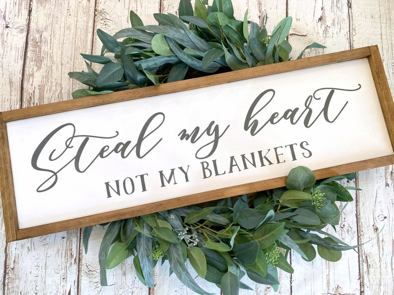 May include: A white wooden sign with a brown frame, featuring the text "Steal my heart, not my blankets" in gray cursive lettering.