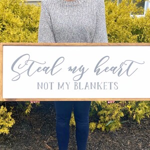 May include: A wooden sign with a white background and a gray inscription that reads "Steal my heart not my blankets".