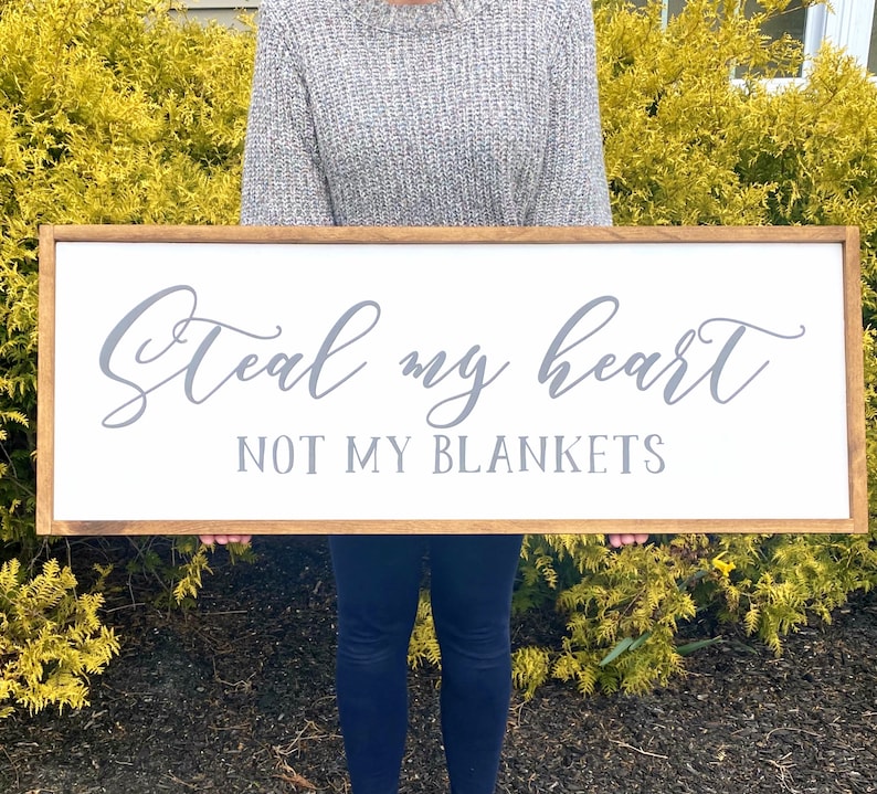 May include: A wooden sign with a white background and a gray inscription that reads "Steal my heart not my blankets".
