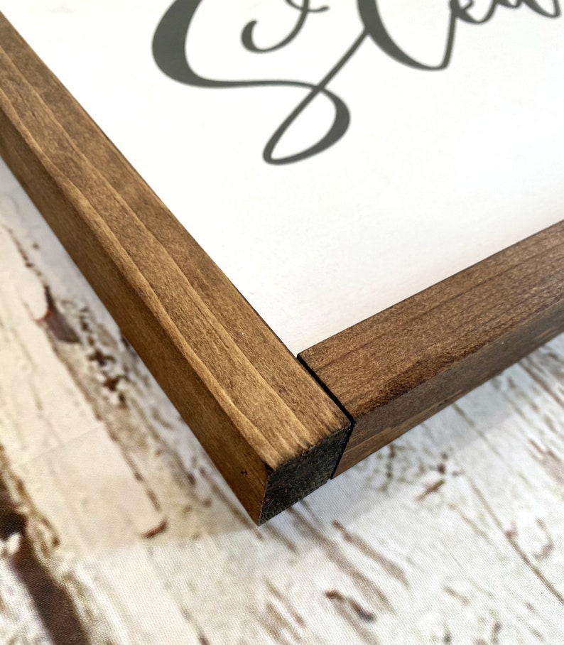 May include: Close-up of the corner of a wooden frame with a dark brown stain. The frame is made of solid wood and has a smooth finish.