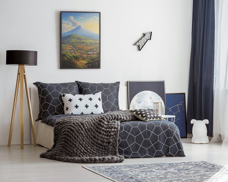 May include: A bedroom with a bed featuring a black and white geometric patterned duvet cover and a gray knitted throw blanket. The bed has a black and white patterned pillow and a white pillow with black crosses. There is a framed landscape painting above the bed, a black arrow wall decor, and a black and white moon print on the wall.