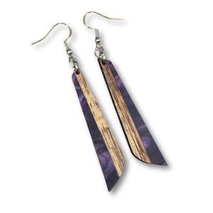 May include: A pair of wooden earrings with silver-colored hooks. The earrings have a rectangular shape with a purple and gold color scheme. The purple section has a marbled effect.