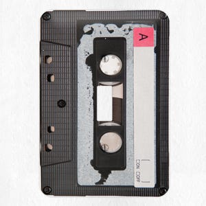 May include: A black cassette tape with a white label. The label has a red sticker with the letter "A" on it. The cassette tape has a black plastic case with a silver metal strip.