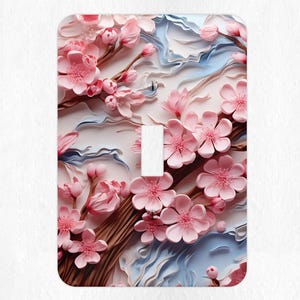 May include: A light switch cover featuring a close-up of pink paper flowers with a textured background. The flowers are arranged in a cluster and appear to be made of paper.