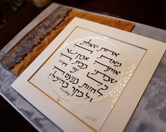 May include: A framed piece of art with a white background and a gold circle with Hebrew text in black ink. The circle is surrounded by a gold leaf design. The text reads "אוהבת אותך" which translates to "I love you".
