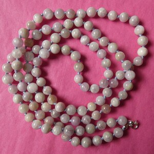 May include: A long strand of light purple beads with a silver clasp. The beads are strung on a light purple cord.