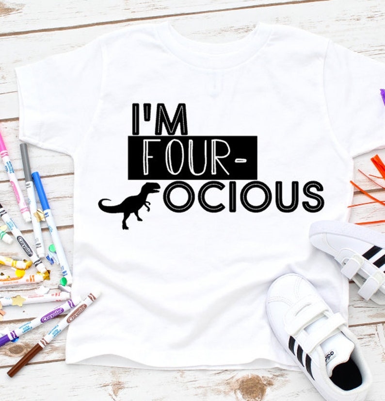 Puede incluir: Camiseta blanca con texto negro que dice "I'm Four-ocious" con una silueta de dinosaurio negro.
