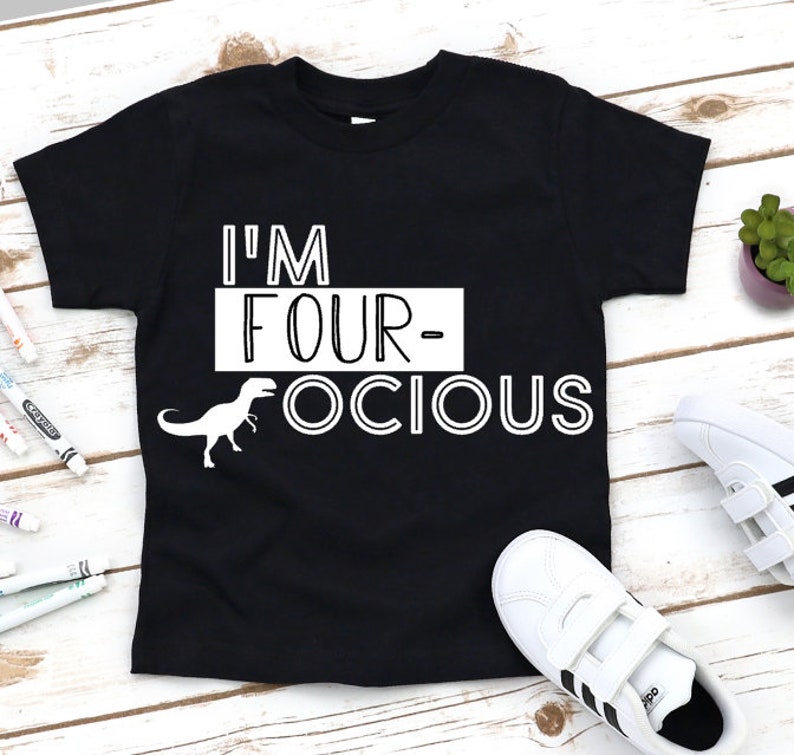 Puede incluir: Camiseta negra con texto blanco que dice "I'm Four-ocious" y una ilustraci&oacute;n de dinosaurio blanca.