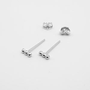 Puede incluir: Un par de pendientes de plata con tres pequeñas cuentas redondas en fila.