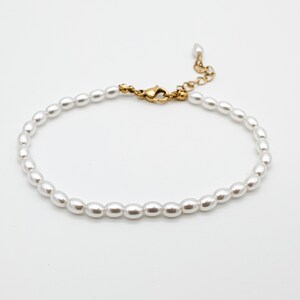 May include: A delicate white pearl bracelet with a gold clasp.